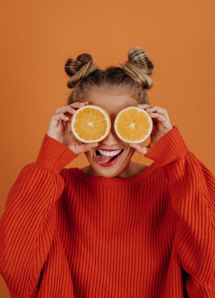 Girl holding up two orange halves over her eyes